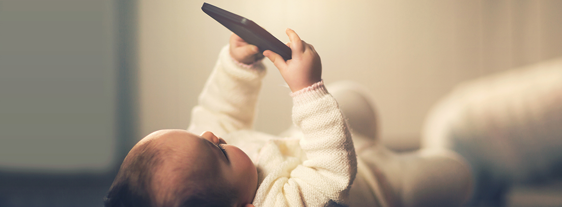 bebé tumbado con un móvil en la mano