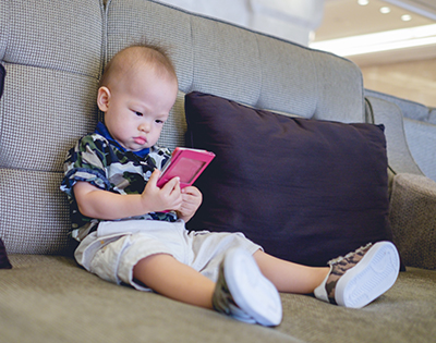 bebé sentado en un sofá con un móvil en las manos