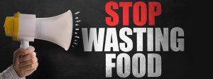 mano sujetando un megafono y una frase escrita "STOP WASTING FOOD"