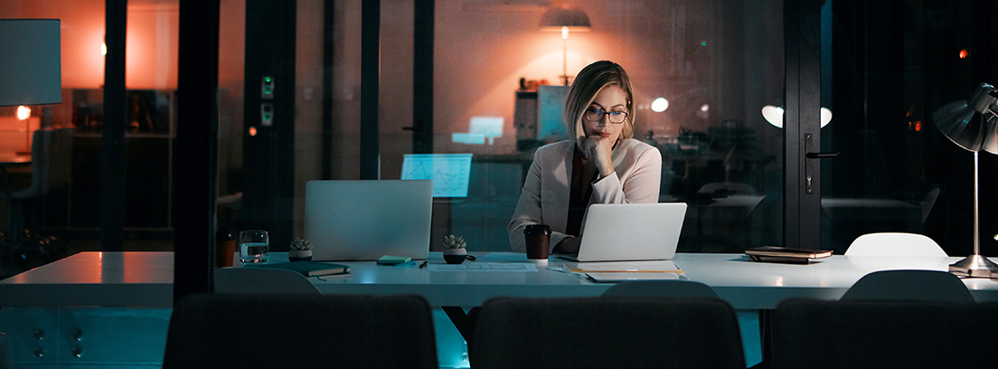 mujer trabajando con un ordenador portátil en la oficina de noche