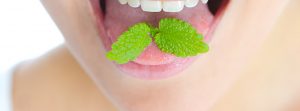 Chica sacando la lengua con una hoja de menta sobre ella