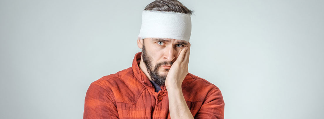 hombre con venda en la cabeza tomándose la cara