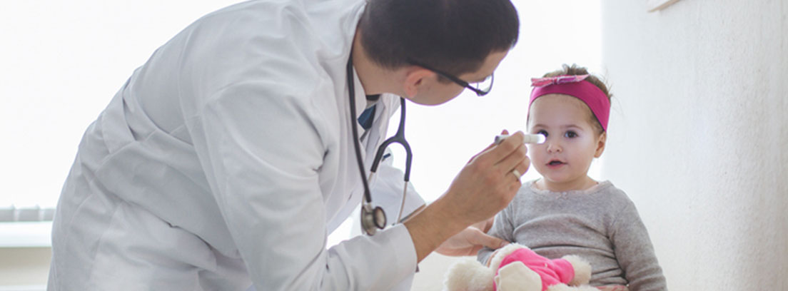 Medico revisando niña los ojos