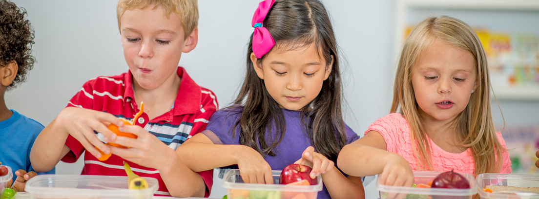 tres niñas tomando alimentos de tuppers