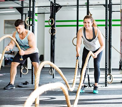 chico y chica en gimnasio realizando ejercicios de fitness con cuerdas