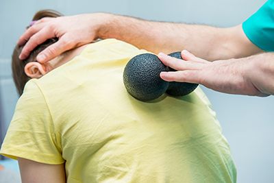 mujer con dos pelotas en las espalda dándose rehabilitación