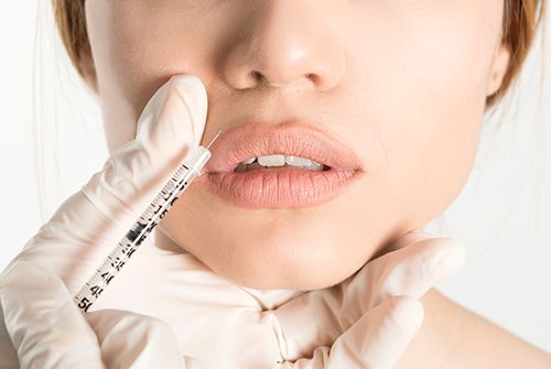 mujer poniendose botox en los labios con una jeringuilla