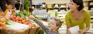 madre con su hijo haciendo la compra en la sección de verduras