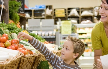 madre con su hijo haciendo la compra en la sección de verduras