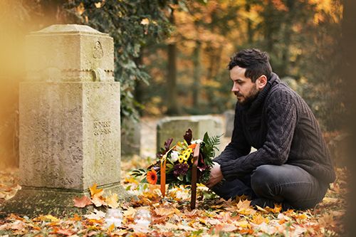 hombre llevando flores a un cementerio