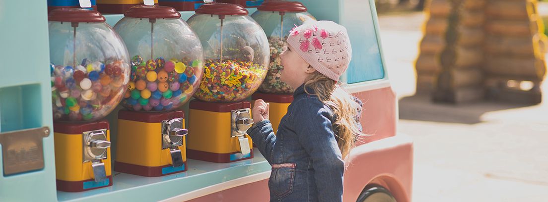 niña mirando diferentes máquinas expendedoras de chicles