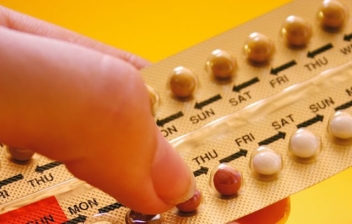 dedos sujetando una tableta de minipíldoras anticonceptivas