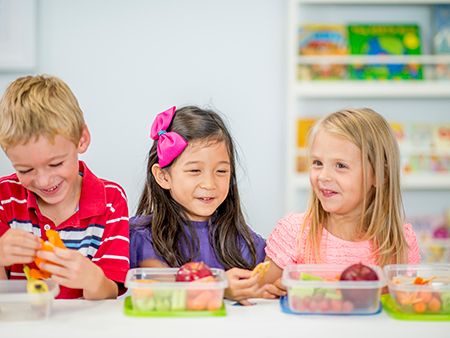 un niño y dos niñas comiendo de tupper