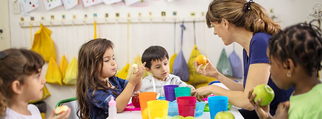 profesora en clase enseñando a comer a niños