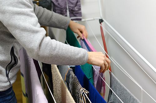 persona tendiendo la ropa en un tendedero dentro de casa