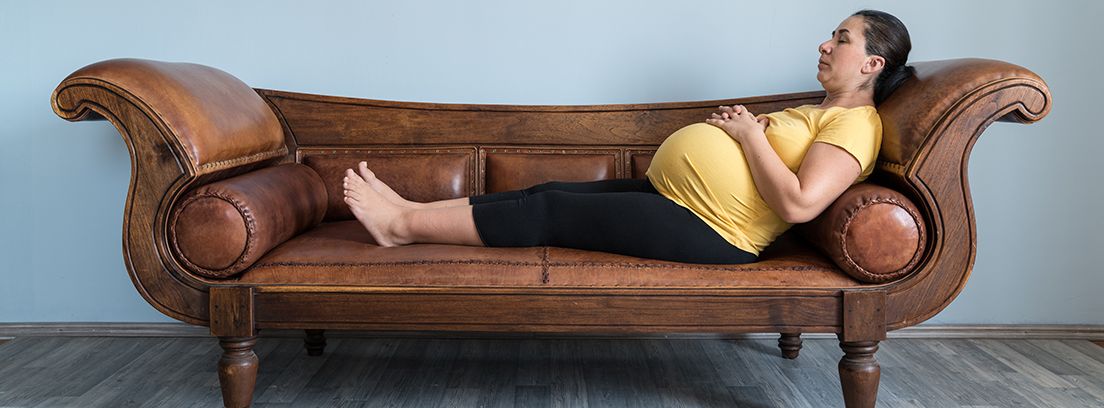 mujer embarazada tumbada en un diván marrón