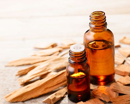 trozos de madera de sándalo y dos frascos de aceite de sándalo