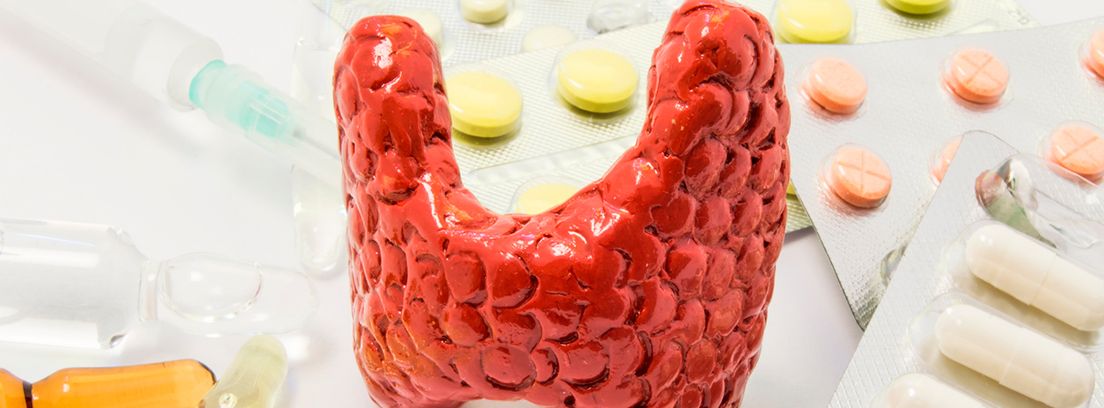 Figura de tiroides rodeada de píldoras, medicamentos, frascos de medicina con jeringa, simbolizando el tratamiento del tiroides con yodo radiactivo