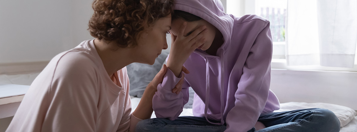 Depresión en la adolescencia: Preocupada mamá consolando a la hija adolescente deprimida llorando en casa