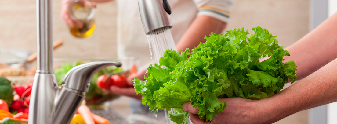 lavando una lechuga bajo el grifo de agua