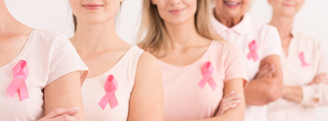 mujeres con camisetas rosas y el lazo representación de cáncer de mama