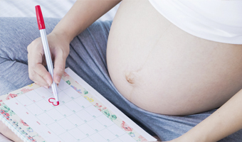 Mujer embarazada tachando días del calendario.