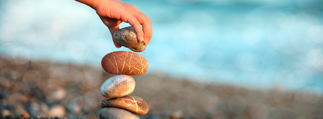 mano poniendo piedra sobre piedra en una playa