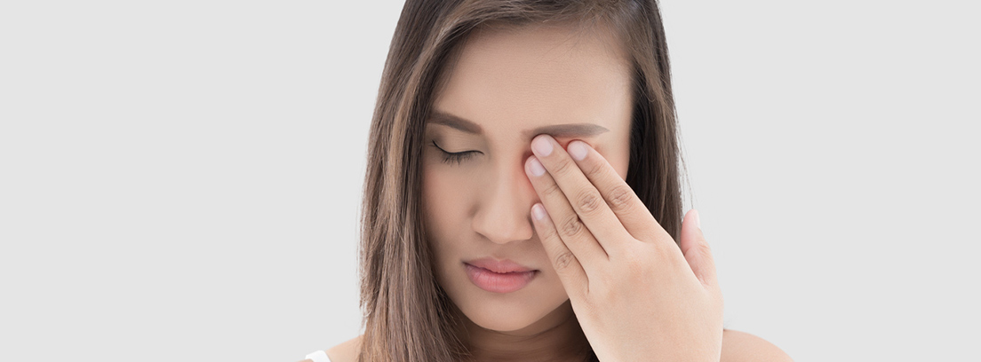 joven con la mano en el ojo y gesto de dolor