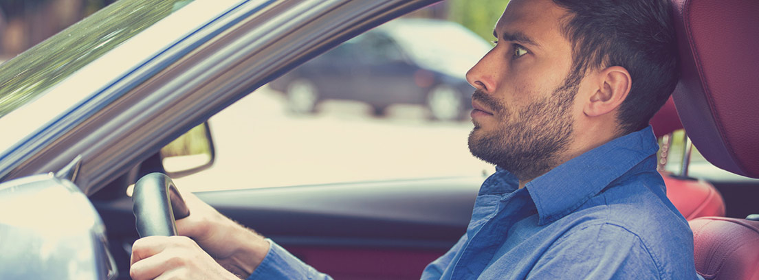 hombre joven al volante de un coche con cara de pánico