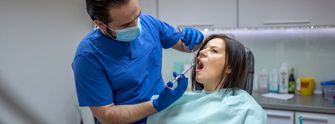 Anestesia bucodental: mujer en la sala del dentista inyectando anestesia local