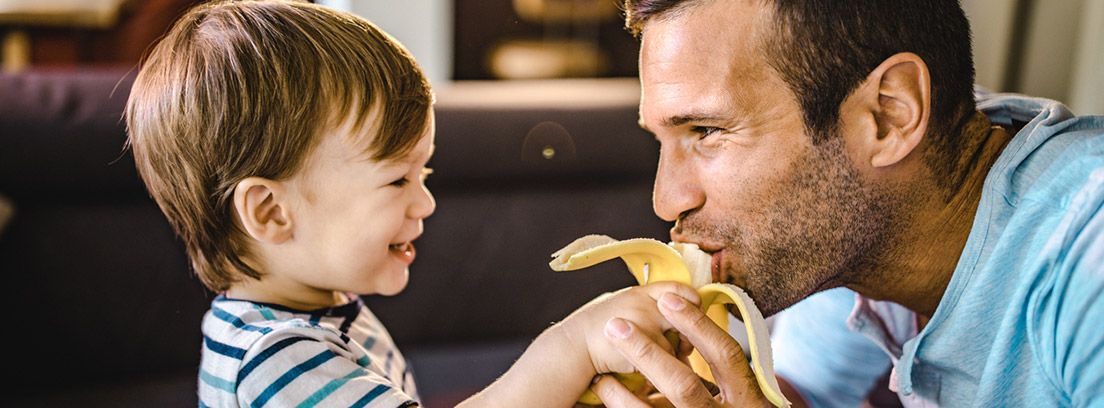 niño dando de comer un plátano a su padre
