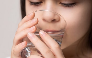Suero oral para combatir la deshidratación en niños : niña bebiendo un baso con suero