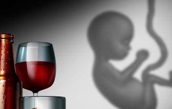 Síndrome alcohólico fetal: botella y copa de vino con un feto al lado en fondo gris