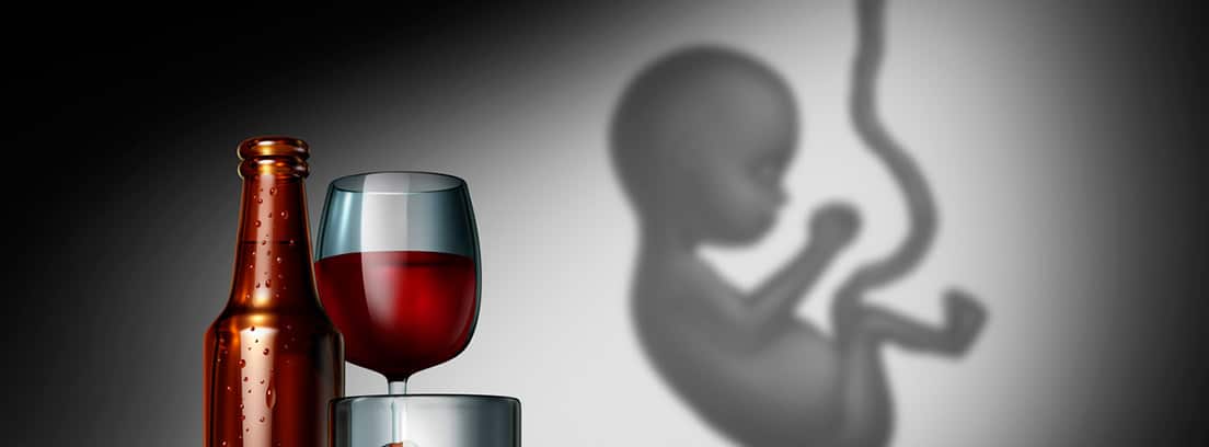 Botella y copa de vino con un feto al lado en fondo gris