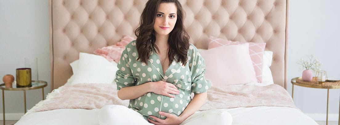 Parto en casa: mujer embarazada sentada encima de la cama
