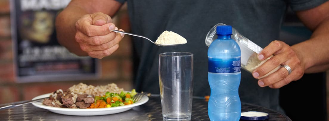 Suplementos deportivos grupo A: hombre añadiendo a un vaso de agua un suplemento alimenticio