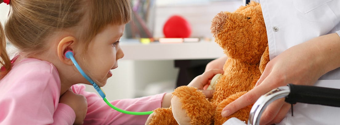 Enfermedad de Leigh: La mano niña con un estetoscopio escuchando el corazón de un oso de peluche en consulta médica