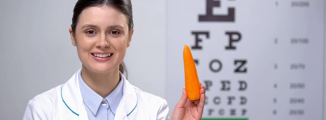 Zanahoria, la hortaliza que cuida tu vista: mujer oftalmólogan con una zanahoria en la mano