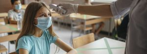 Tomando la temperatura en el colegio a una niña con mascarilla