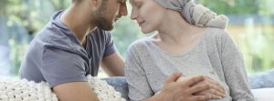 Cáncer en el embarazo: pareja con las manos enlazadas enlazadas , mujer embarazada y con pañuelo en la cabeza