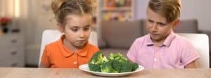 Falta de apetito en niños: niño y niña mirando un plato con brócoli