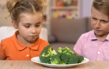 Falta de apetito en niños: niño y niña mirando un plato con brócoli