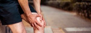 Lesiones musculares: hombre deportista con las anos en la rodilla, síntoma de dolor
