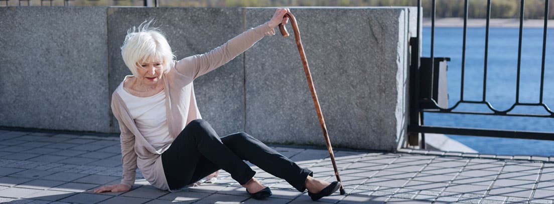 Síndrome post caída: caída de mujer mayor en la calle apoyándose en un bastón