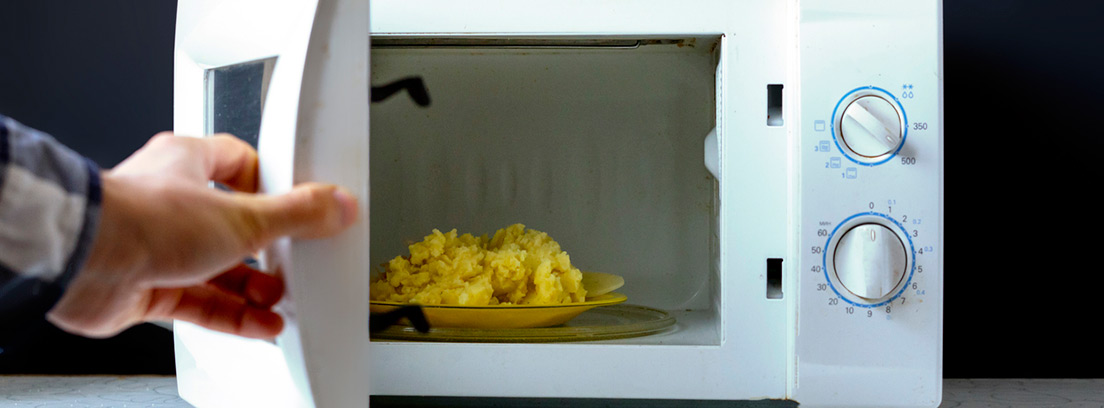 Cocinar en microondas: plato con patatas dentro de un microondas con la puerta abierta