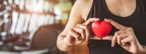 Síndrome del corazón de atleta: mujer deportista con un corazón de plástico en las manos