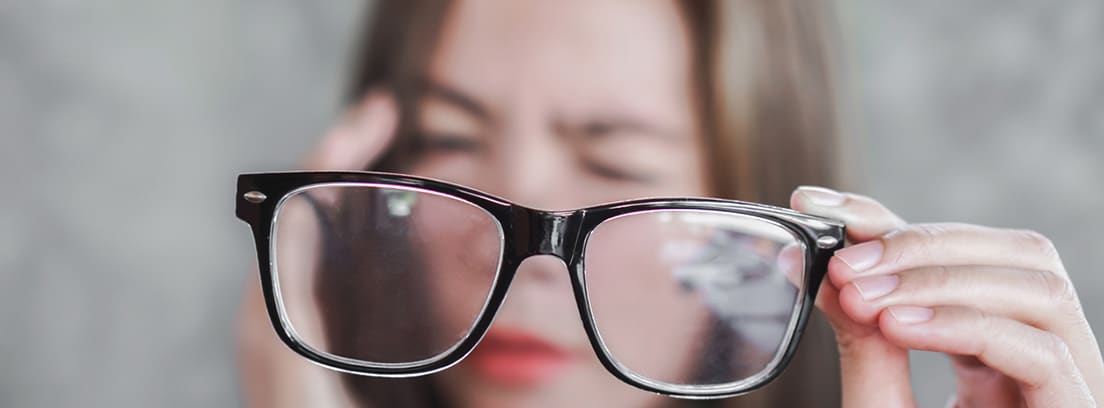 Visión borrosa repentina: Mujer sosteniendo anteojos con dolor de cabeza por visión borrosa de ojos
