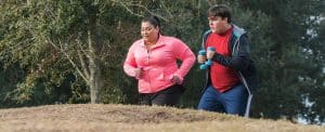 Estudio científico que confirma la necesidad del ejercicio para perder grasa: Un hombre y una mujer con exceso de peso realizando ejercicio por el campo