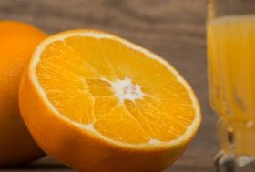 La naranja, mucho más que vitamina C: naranja partida por la mitad y un vaso de zumo al lado