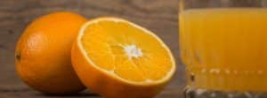 La naranja, mucho más que vitamina C: naranja partida por la mitad y un vaso de zumo al lado